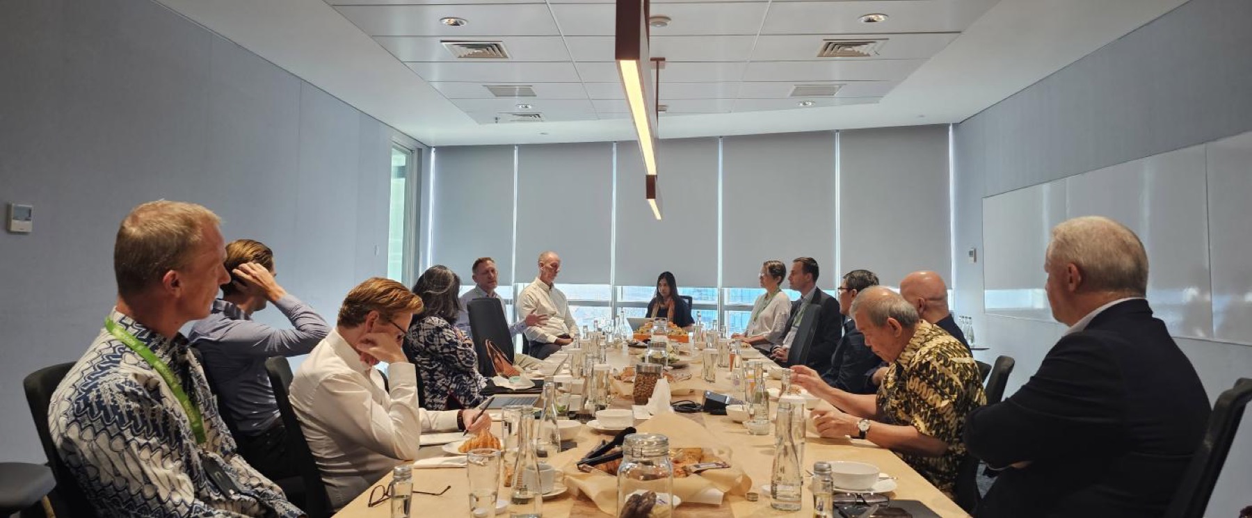 A roundtable in a bright meeting room, pastries and water on the table