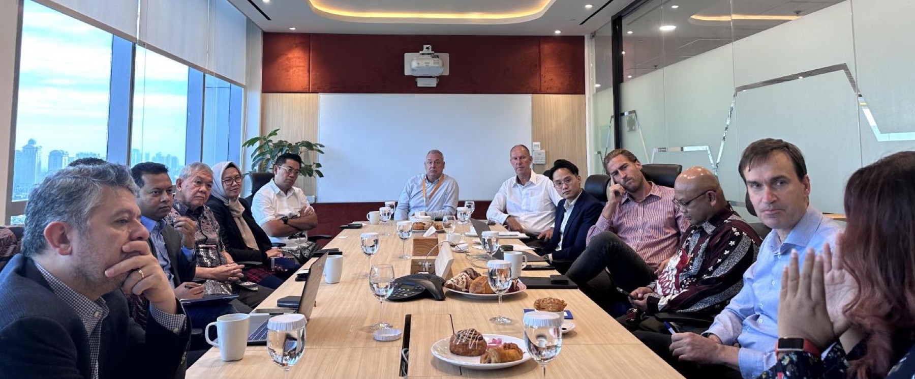 A boardroom meeting beside a window, the Jakarta skyline visible outside